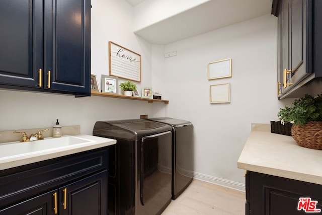 laundry area featuring cabinets, washing machine and dryer, sink, and light hardwood / wood-style flooring