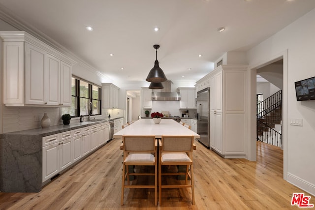 kitchen featuring stainless steel appliances, white cabinetry, sink, and pendant lighting