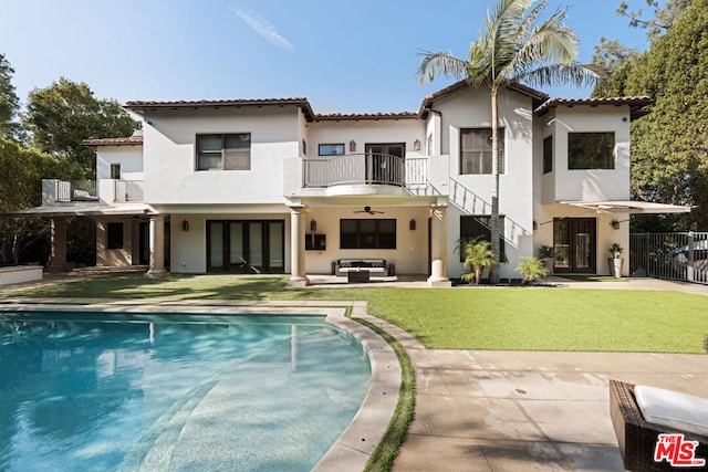 rear view of property featuring a fenced in pool, a balcony, ceiling fan, an outdoor living space, and a patio area