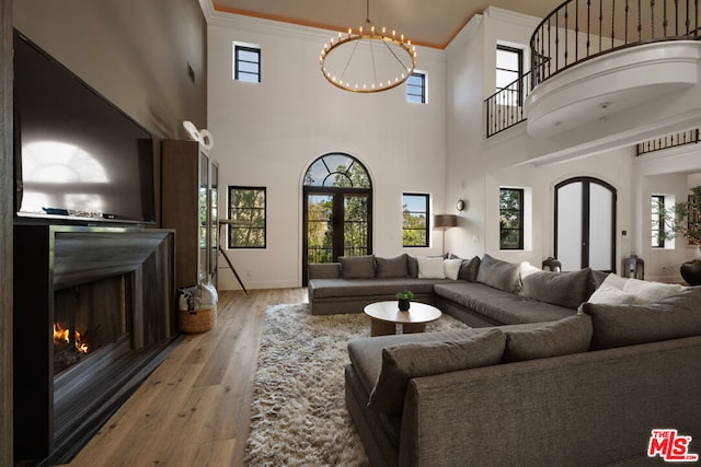 living room featuring a healthy amount of sunlight, light hardwood / wood-style floors, french doors, and a chandelier