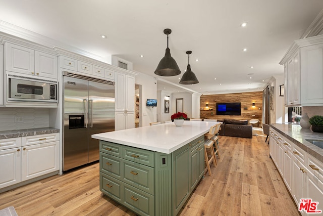 kitchen with white cabinetry, built in appliances, light hardwood / wood-style floors, green cabinetry, and a kitchen island