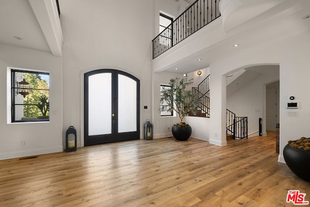 foyer featuring french doors, a high ceiling, and light wood-type flooring