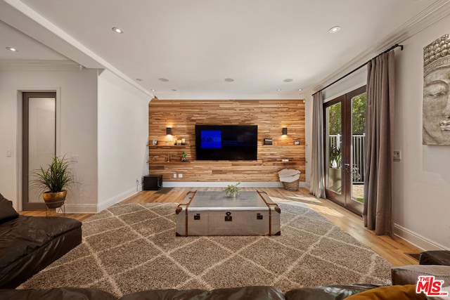 living room featuring crown molding, light wood-type flooring, french doors, and wood walls