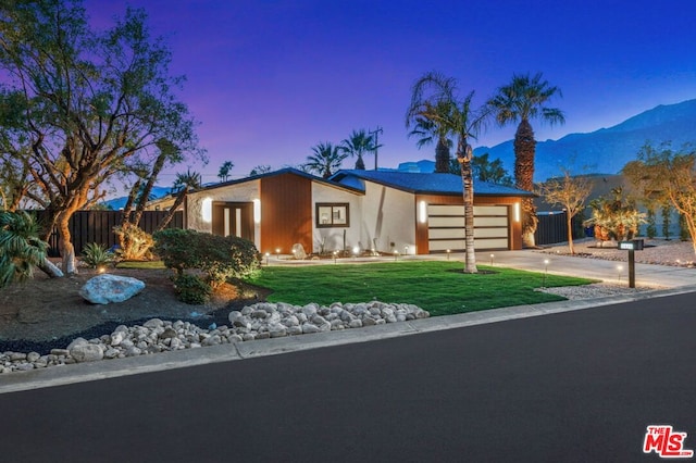 view of front facade featuring a mountain view, a garage, and a lawn