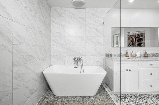 bathroom with tile patterned floors, a tub to relax in, and tile walls