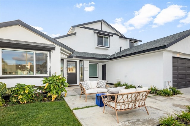 back of house with a garage, outdoor lounge area, and a patio