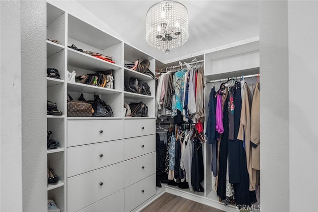 walk in closet featuring wood-type flooring and a notable chandelier