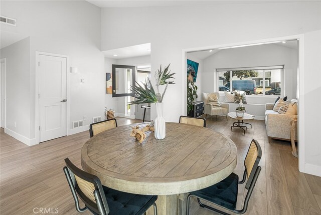 dining area featuring vaulted ceiling and light hardwood / wood-style flooring