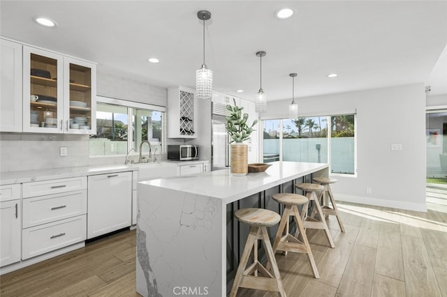 kitchen featuring light hardwood / wood-style flooring, white cabinetry, hanging light fixtures, a center island, and white dishwasher