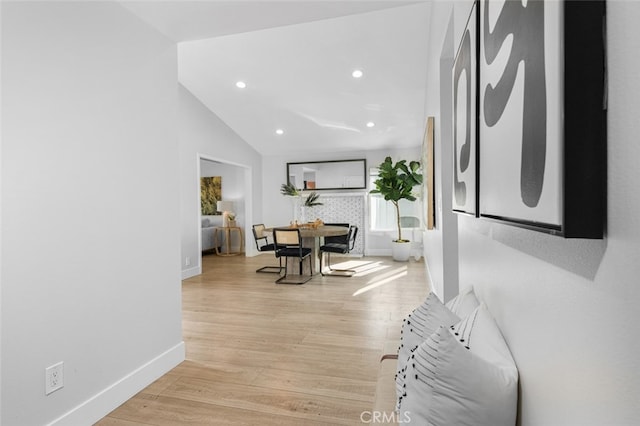 hallway featuring lofted ceiling and light hardwood / wood-style flooring