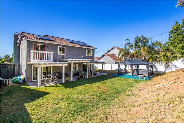 rear view of property featuring a patio, a pergola, a hot tub, a gazebo, and solar panels