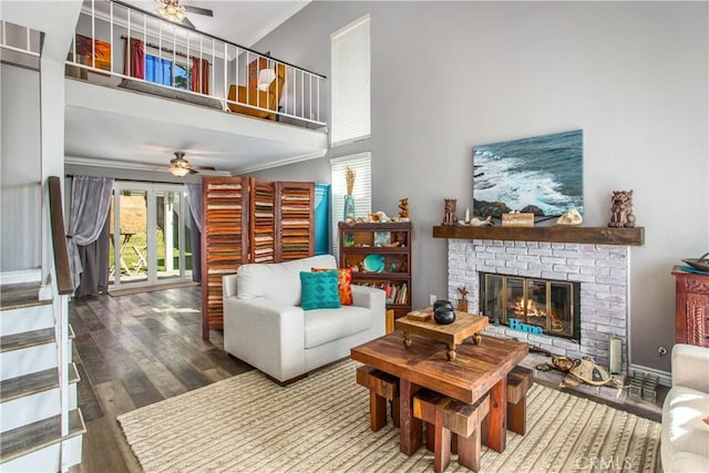 living room featuring hardwood / wood-style flooring, ceiling fan, ornamental molding, and a brick fireplace