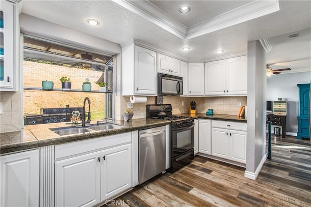 kitchen with sink, crown molding, a tray ceiling, black appliances, and white cabinets