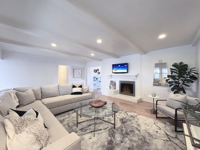 living room featuring beamed ceiling, a fireplace, and light hardwood / wood-style floors