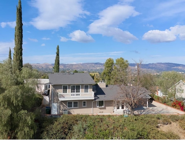 rear view of property featuring a mountain view and a balcony