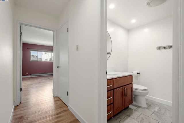 bathroom featuring hardwood / wood-style flooring, vanity, baseboard heating, and toilet