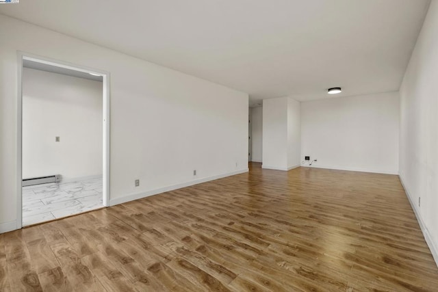 empty room with a baseboard heating unit and wood-type flooring