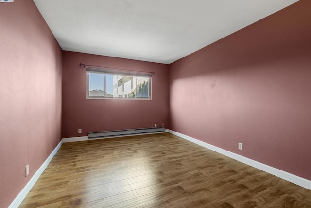 empty room with baseboard heating and hardwood / wood-style flooring