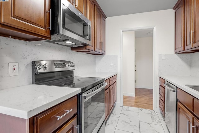 kitchen featuring light stone counters, decorative backsplash, and stainless steel appliances