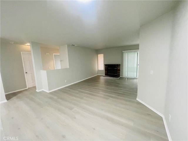 unfurnished living room featuring a brick fireplace and light hardwood / wood-style floors