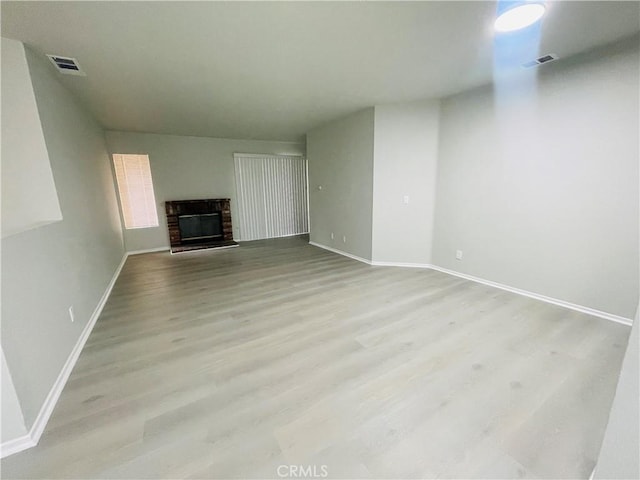 unfurnished living room featuring a brick fireplace and light hardwood / wood-style flooring