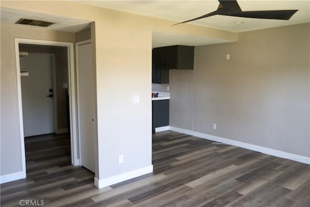 unfurnished room featuring dark wood-style flooring, baseboards, a ceiling fan, and visible vents