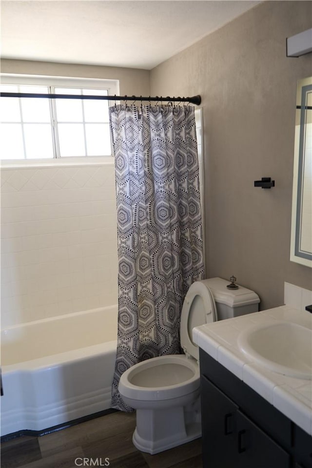 full bath featuring toilet, wood finished floors, vanity, and shower / tub combo with curtain
