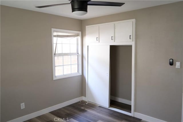 unfurnished bedroom featuring ceiling fan, a closet, dark wood-style flooring, and baseboards