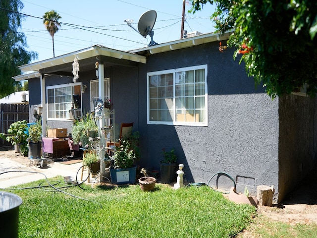 view of front of home with a patio, stucco siding, fence, and a front lawn