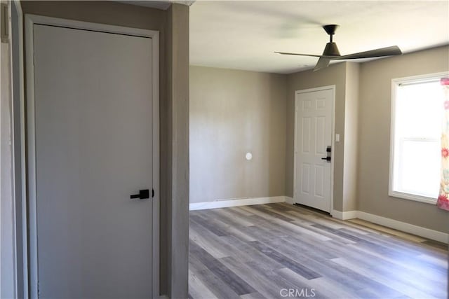 interior space featuring ceiling fan, baseboards, and wood finished floors