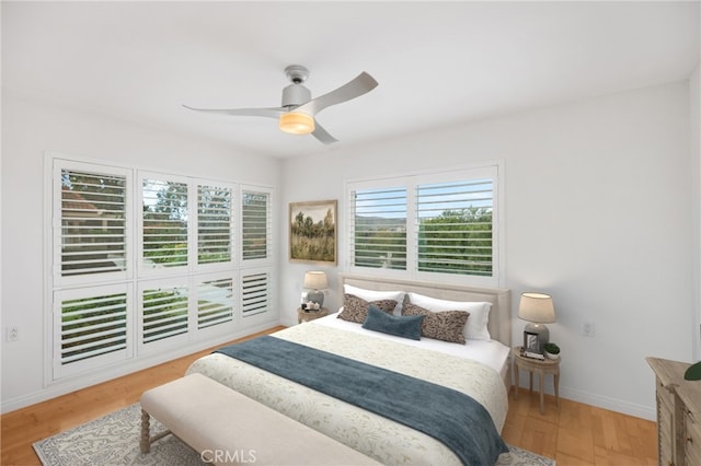 bedroom featuring multiple windows, wood-type flooring, and ceiling fan