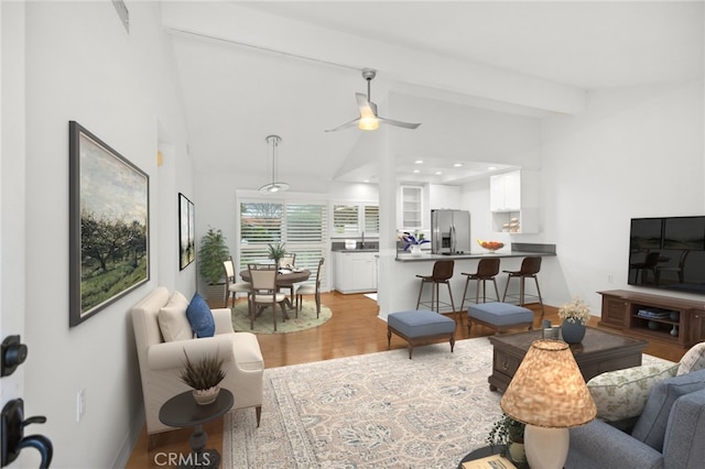 living room featuring ceiling fan, beamed ceiling, and light wood-type flooring