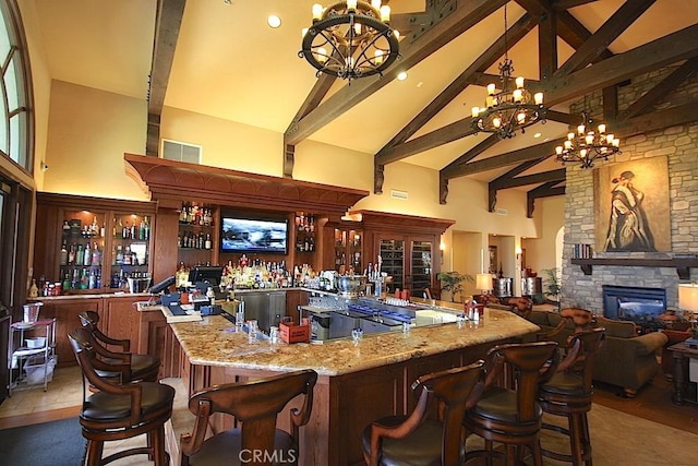 bar featuring light stone counters, dark tile patterned flooring, high vaulted ceiling, and a notable chandelier