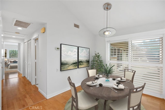 dining room with vaulted ceiling and light hardwood / wood-style flooring