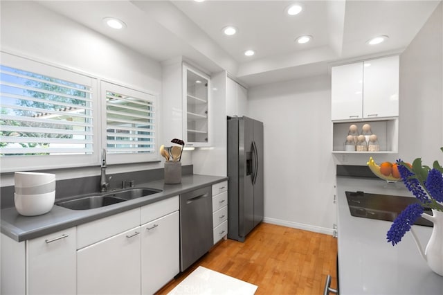 kitchen with sink, a raised ceiling, stainless steel appliances, light hardwood / wood-style floors, and white cabinets