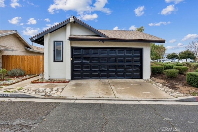 view of front facade featuring concrete driveway, fence, and stucco siding