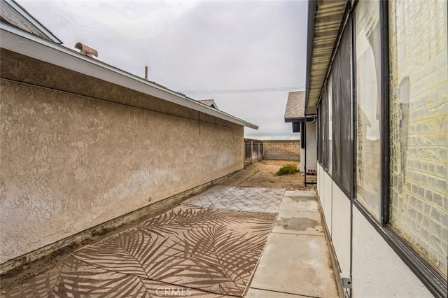 view of side of property with a patio, fence, and stucco siding