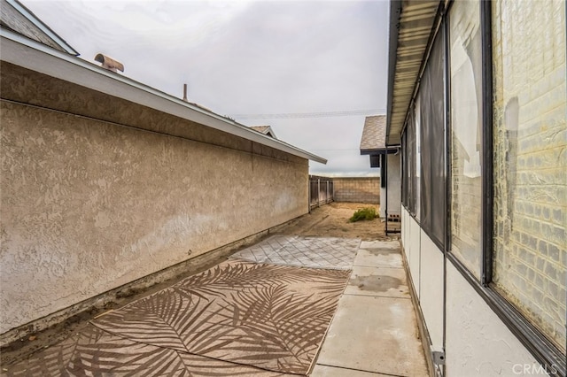 view of side of home with fence, stucco siding, and a patio area