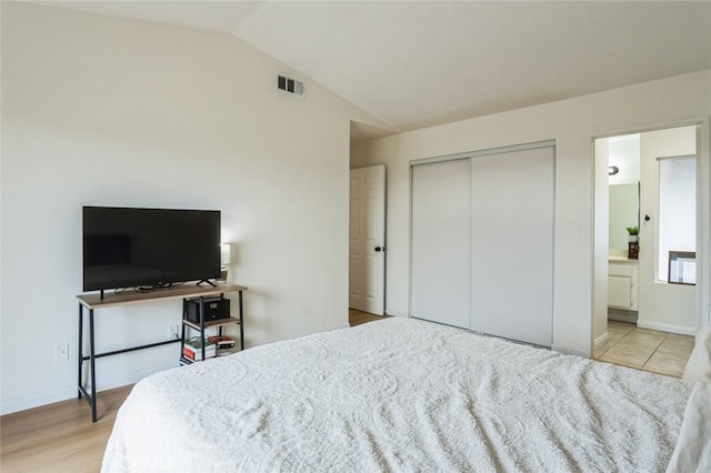 bedroom featuring visible vents, a closet, lofted ceiling, baseboards, and connected bathroom