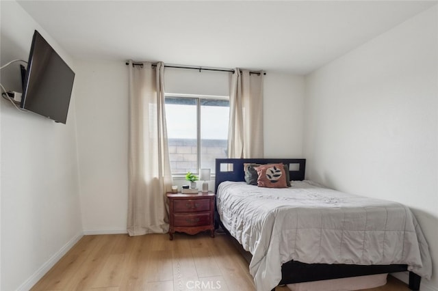 bedroom with light wood finished floors and baseboards