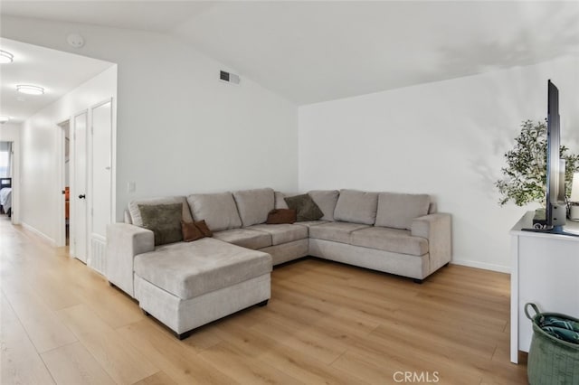 living area with light wood-type flooring, baseboards, visible vents, and lofted ceiling