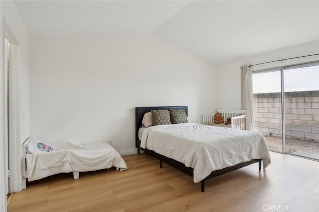 bedroom with light wood-type flooring, access to exterior, and lofted ceiling