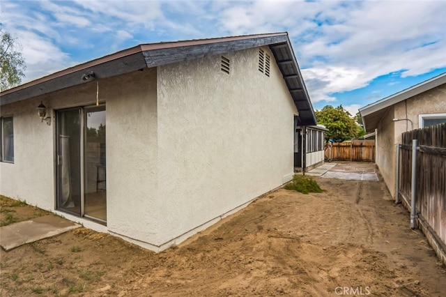 view of side of property featuring fence and stucco siding