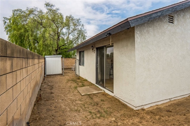 view of side of property featuring fence and stucco siding