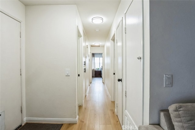 hallway featuring stairs, light wood finished floors, visible vents, and baseboards