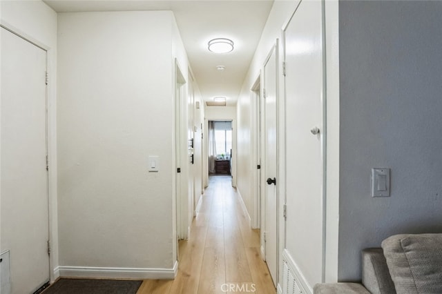 hallway featuring light wood-type flooring, baseboards, and visible vents