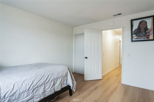 bedroom with light wood-type flooring, visible vents, and baseboards