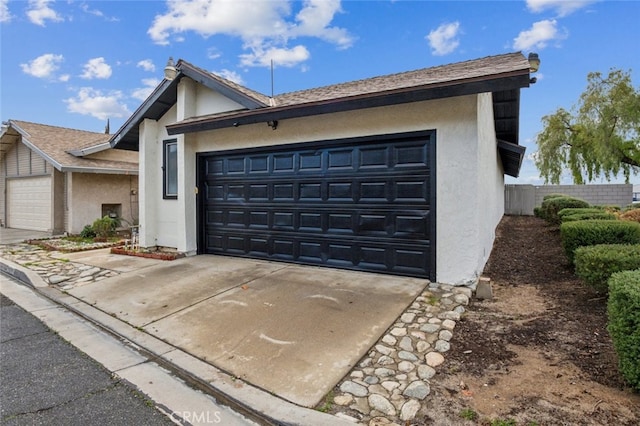 view of front of home featuring concrete driveway, a garage, fence, and stucco siding