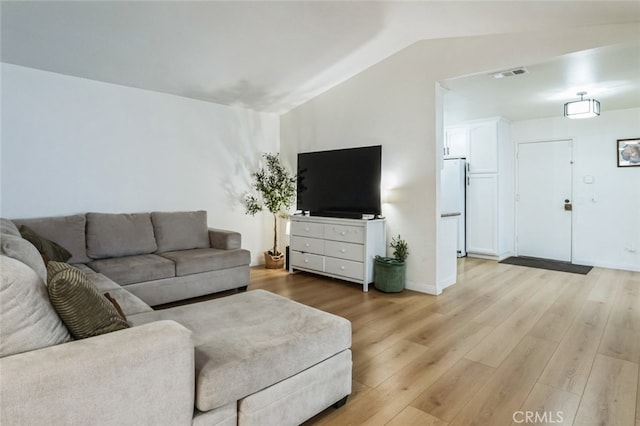 living room with visible vents, vaulted ceiling, and light wood-style flooring