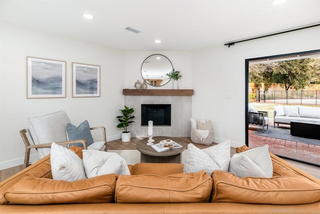 living room featuring a tiled fireplace and hardwood / wood-style flooring